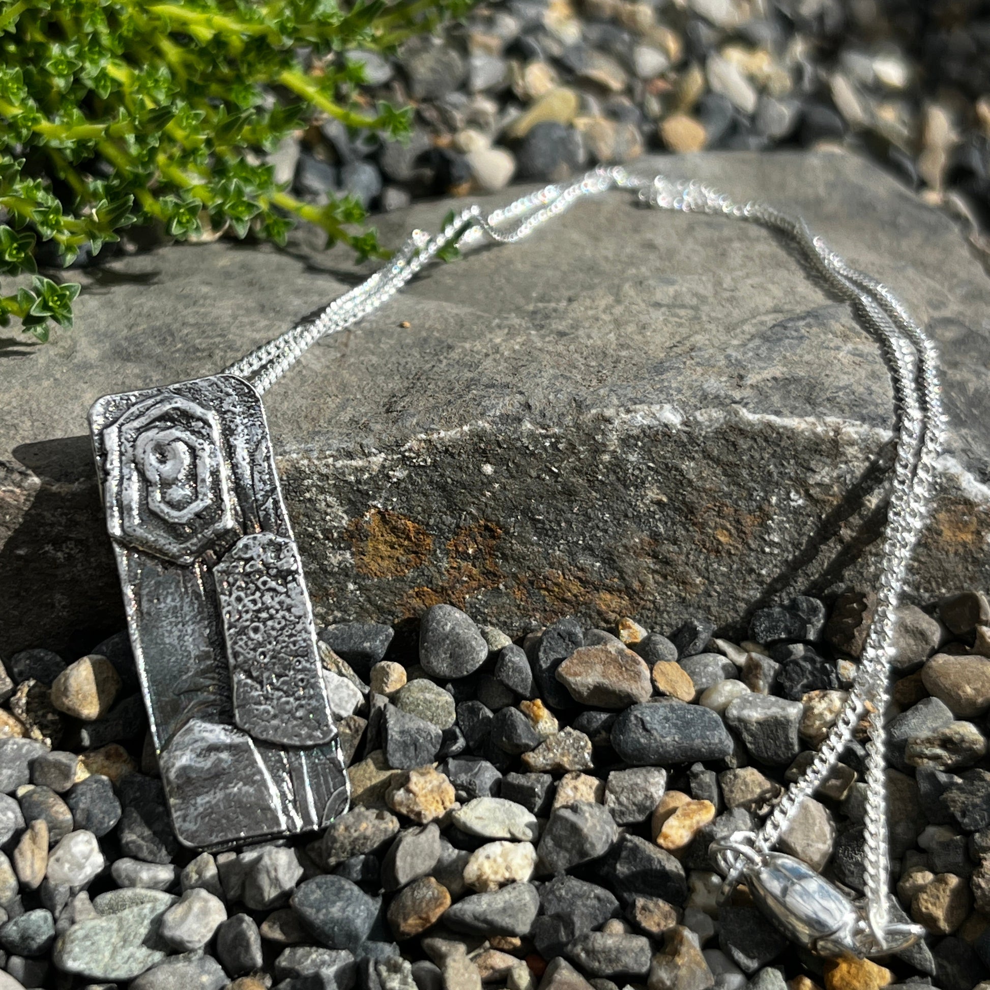 Silver necklace with a pendant on a stone surface