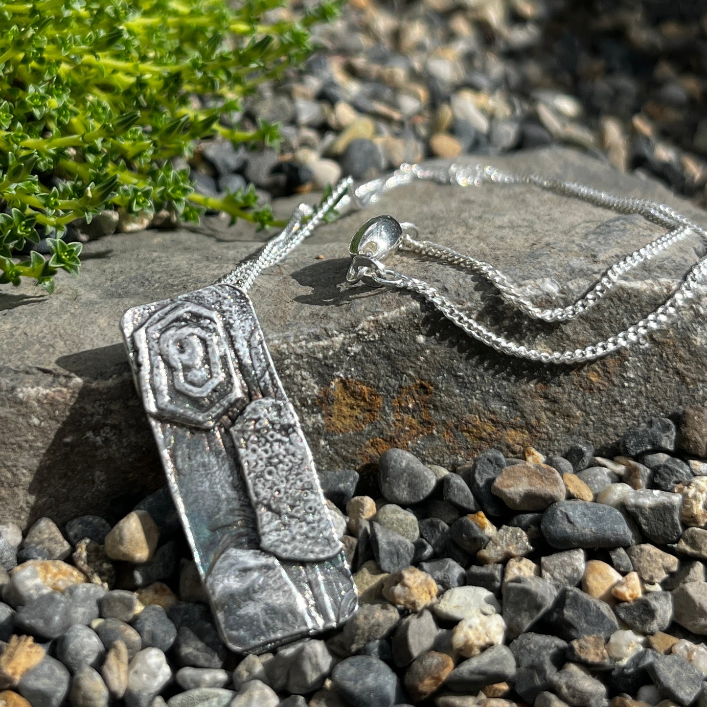 Silver necklace with a pendant on a stone surface