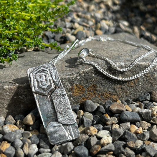 Silver necklace with a pendant on a stone surface