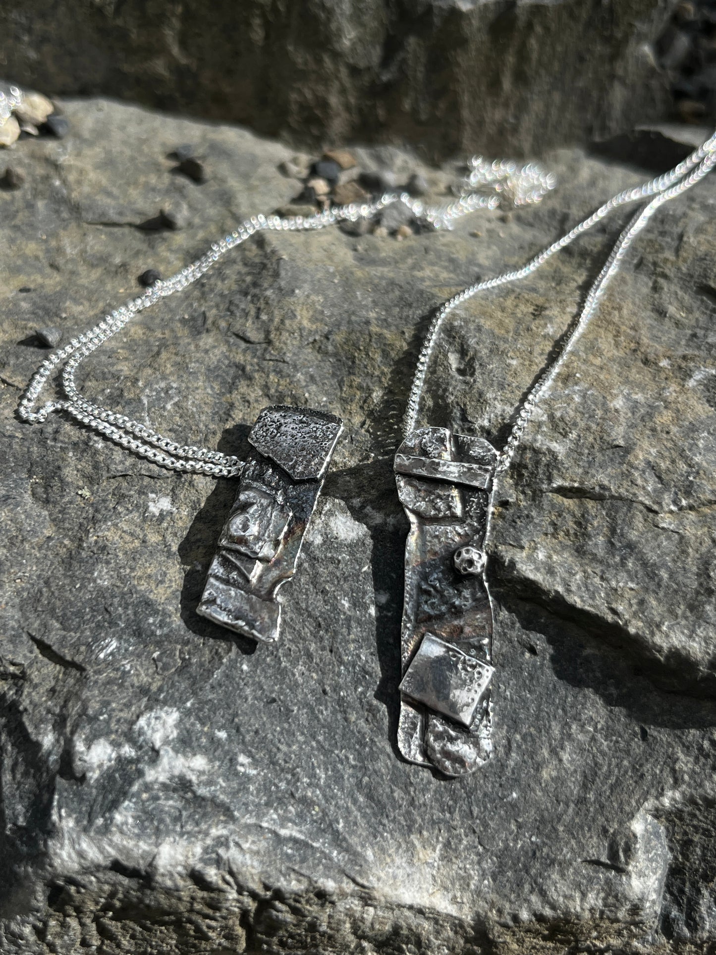 Silver necklace with pendant on a rocky surface
