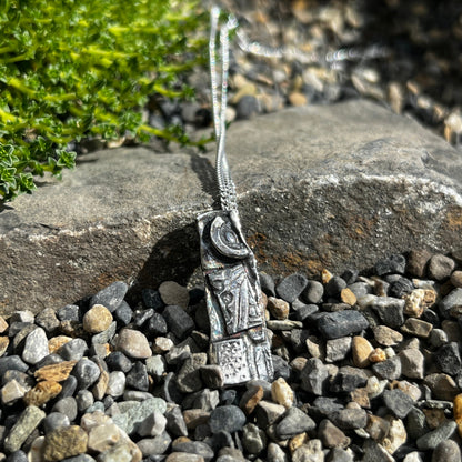 Silver necklace with a pendant on a stone surface