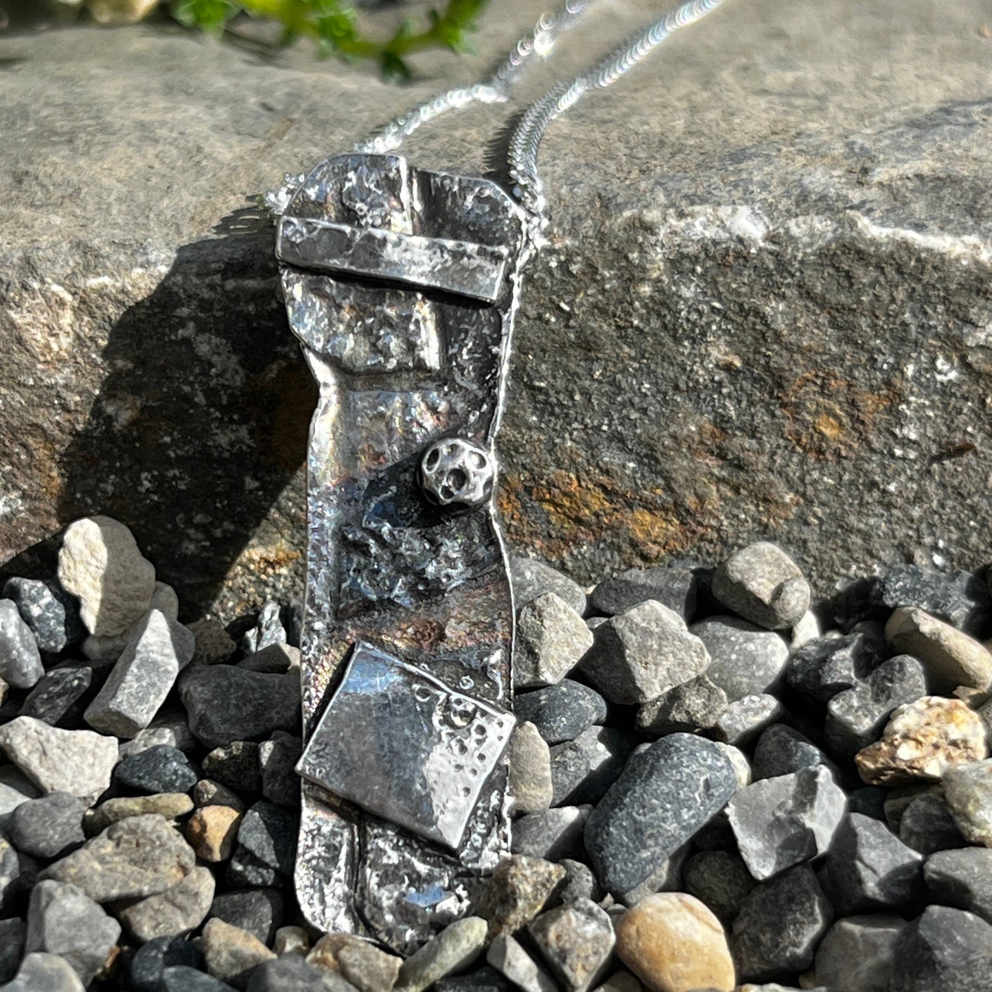 Silver necklace with a bow pendant on a stone surface