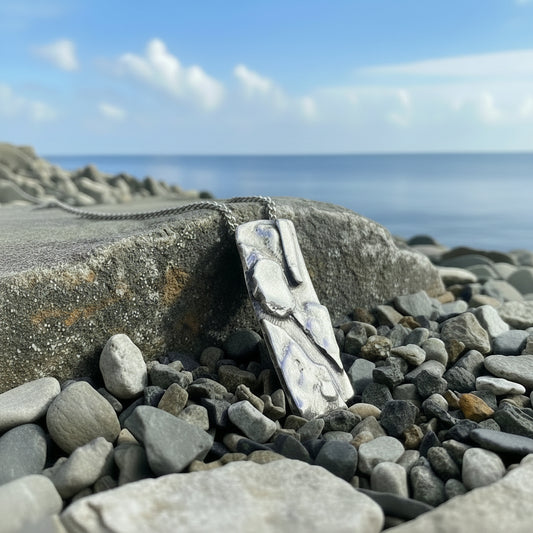 Silver necklace with a pendant on a rocky surface