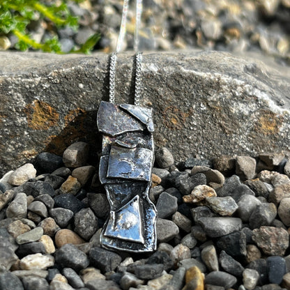 Sterling silver  pendant on a chain against a stone and pebble background