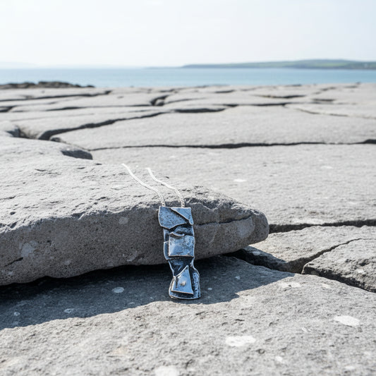 Sterling silver  pendant on a chain against a stone and pebble background