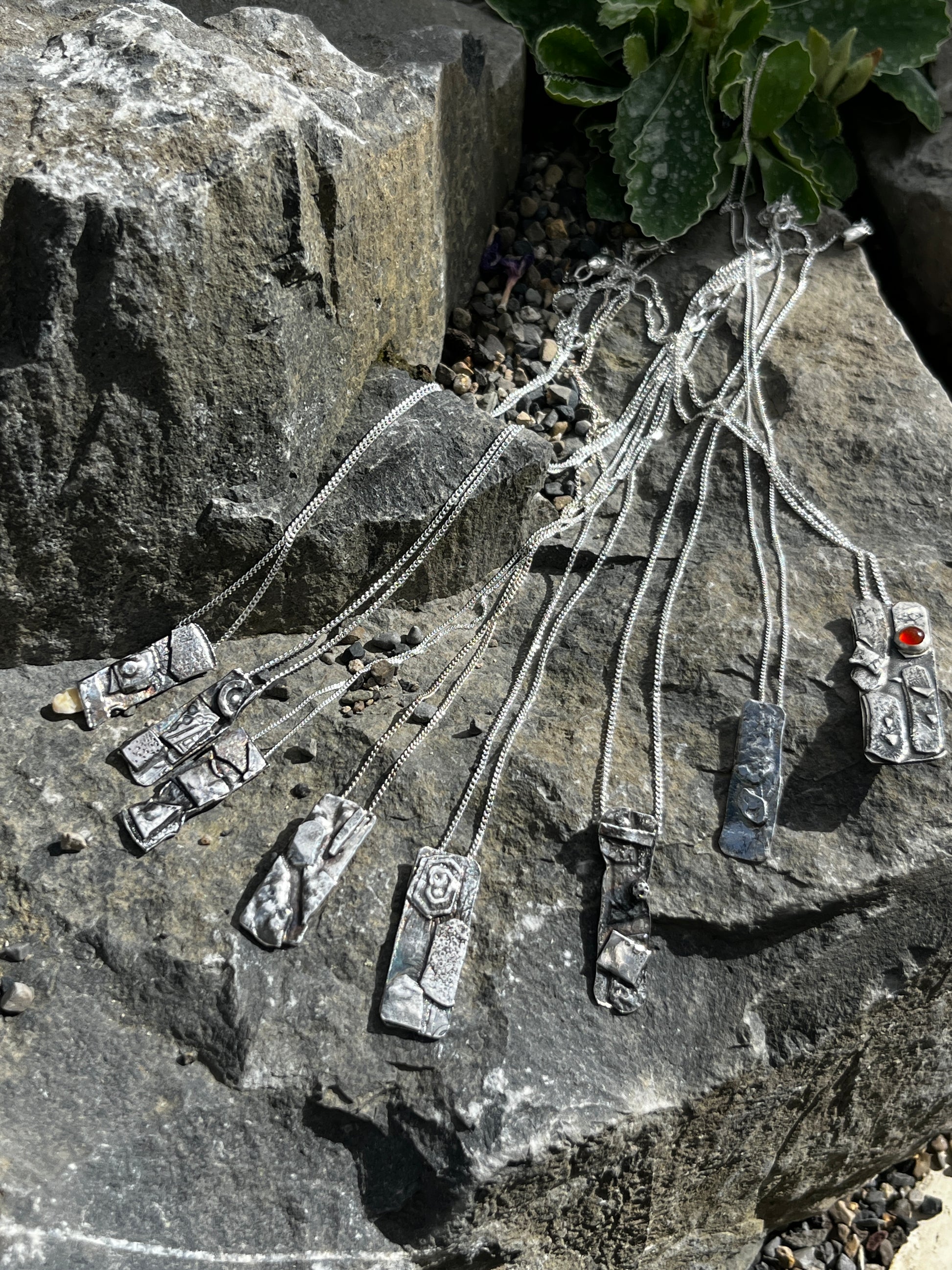 Silver jewellery set on a stone surface with greenery reflecting the landscape of the burren