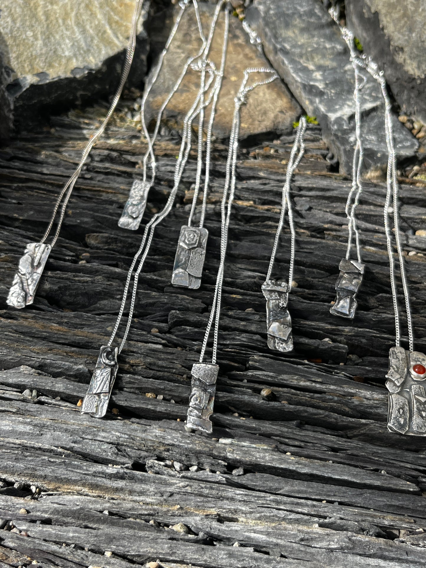 Metallic necklace with pendants on a textured stone surface