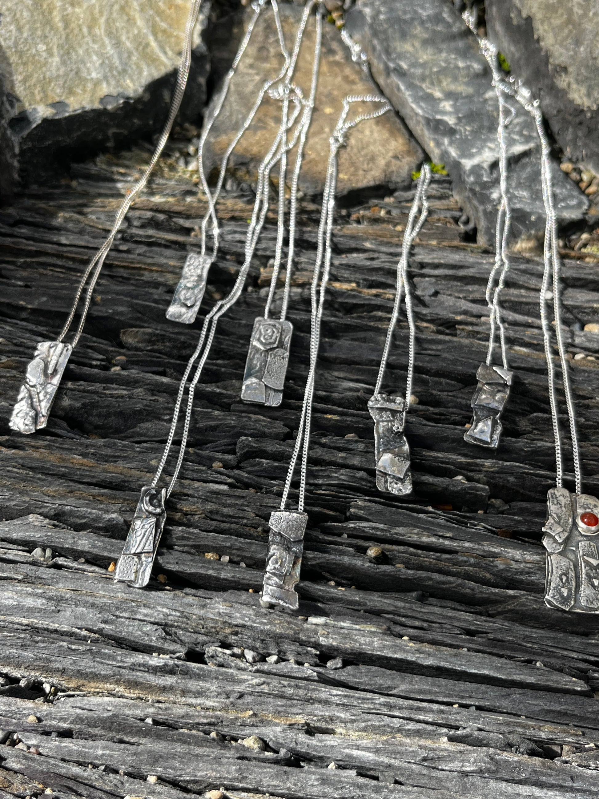 Metallic necklace with pendants on a textured stone surface