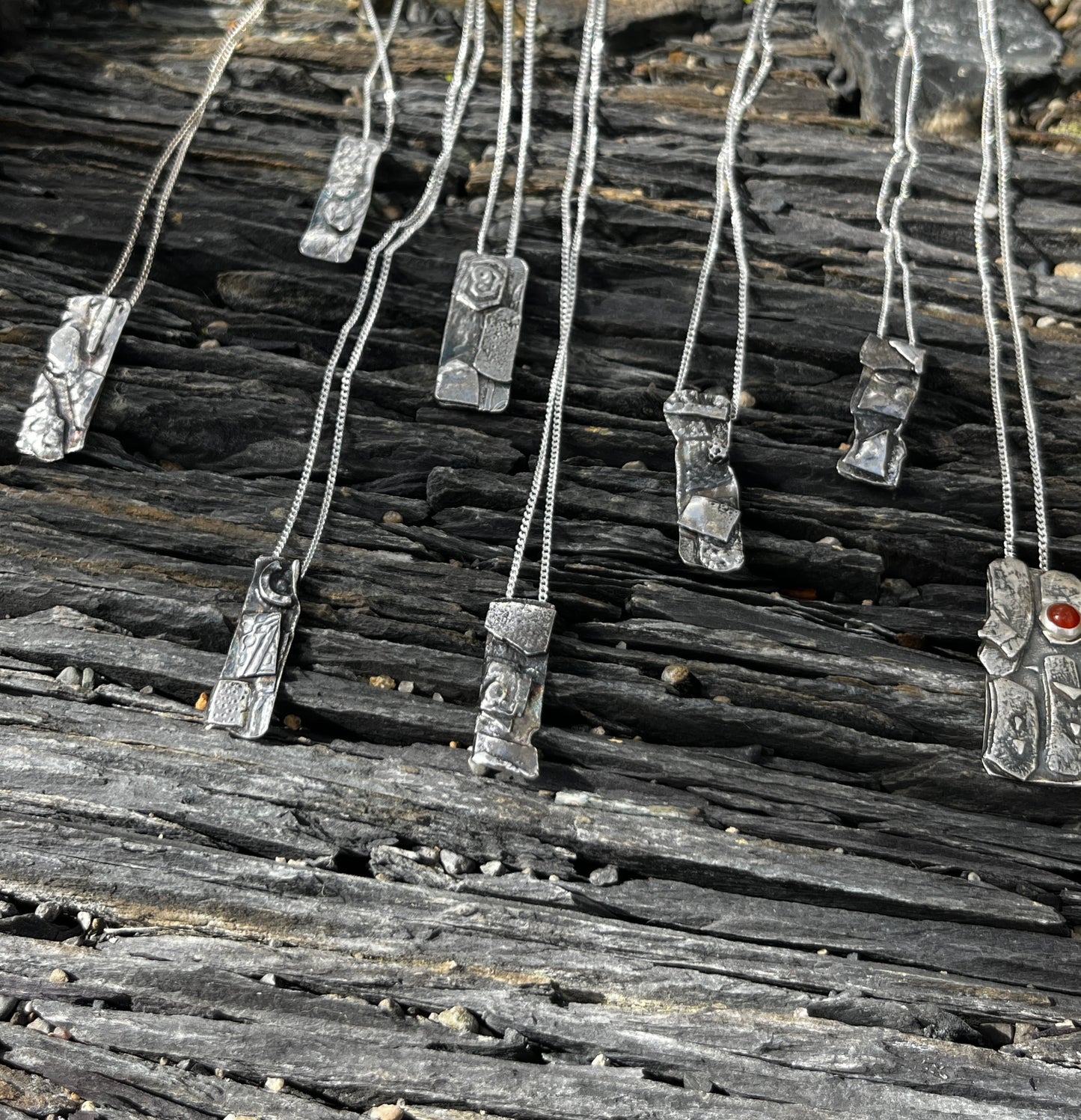 Silver necklaces with unique pendants on a wooden surface