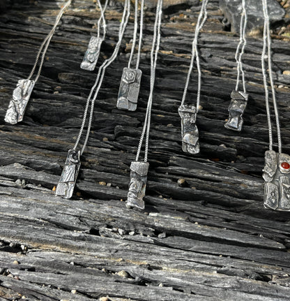 Silver necklaces with unique pendants on a wooden surface