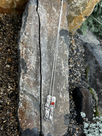 Silver necklace with red stone on a stone surface