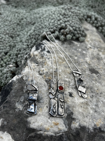 Silver jewelry with gemstones on a textured stone surface