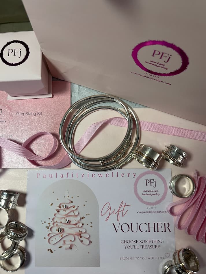 Paula Fitzjewellery gift set with rings, card, and packaging on a pink surface.