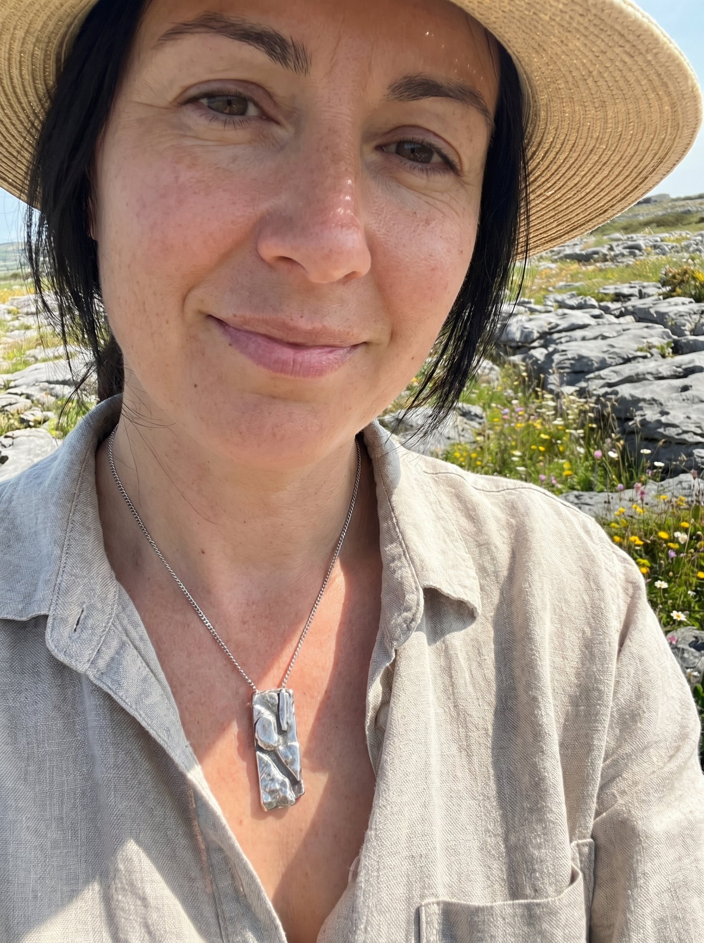 Woman wearing a straw hat and light shirt with a scenic background