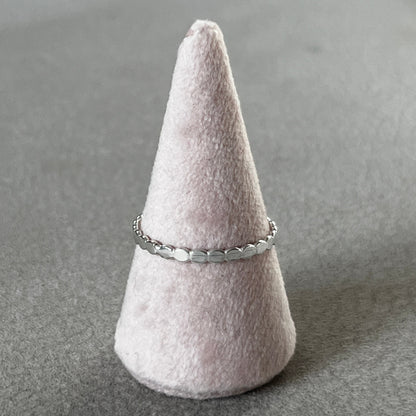 Silver ring on a cone-shaped felt stand against a gray background