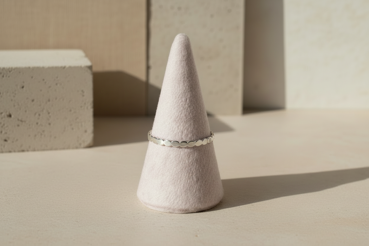 Silver ring on a cone-shaped white object against a neutral background