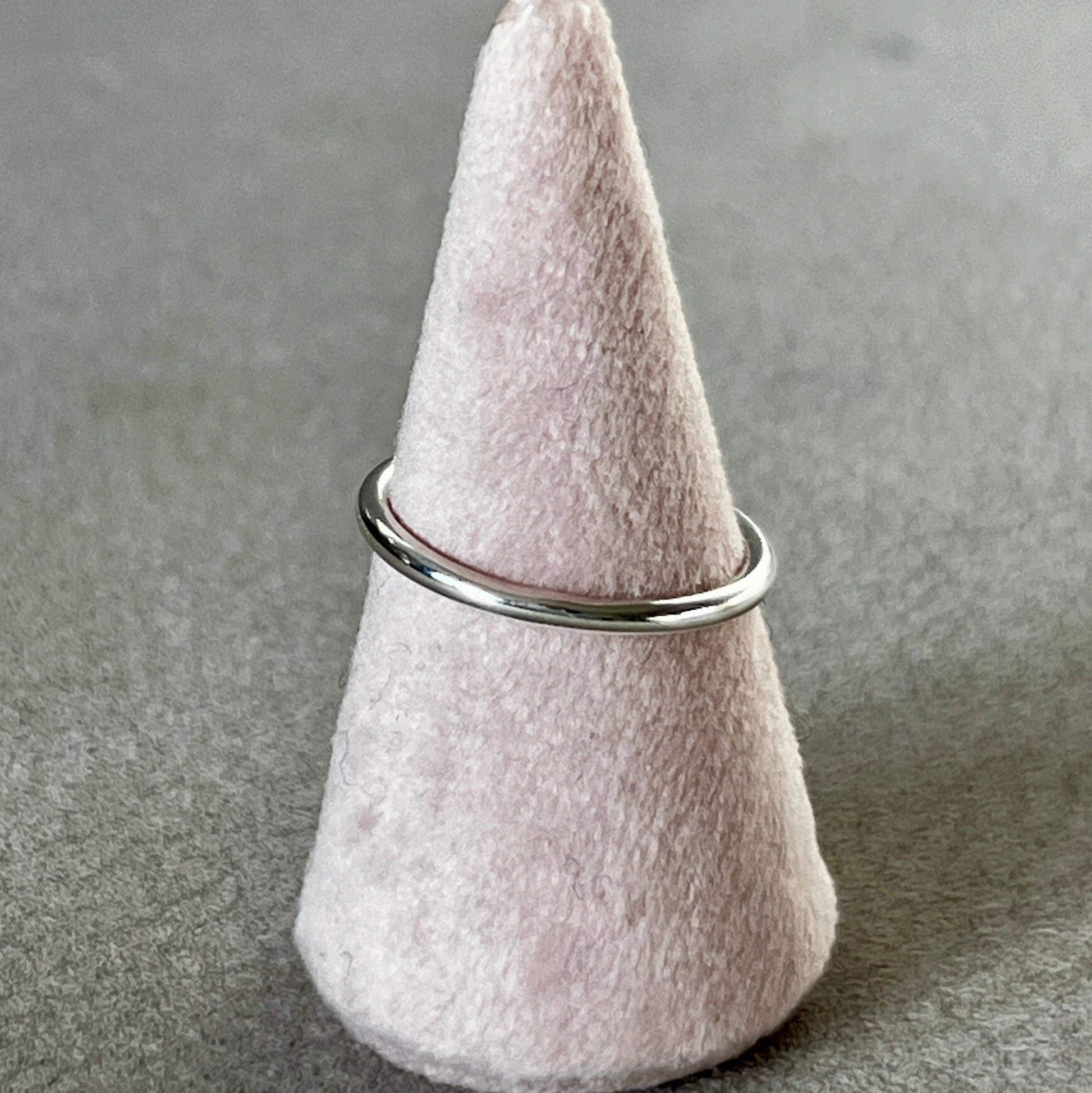 Felted cone-shaped object with a metal ring on a gray surface
