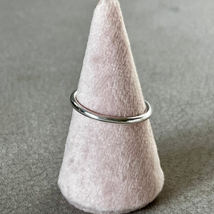 Felted cone-shaped object with a metal ring on a gray surface