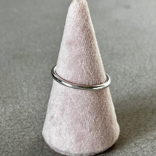 Felted cone-shaped object with a metal ring on a gray surface