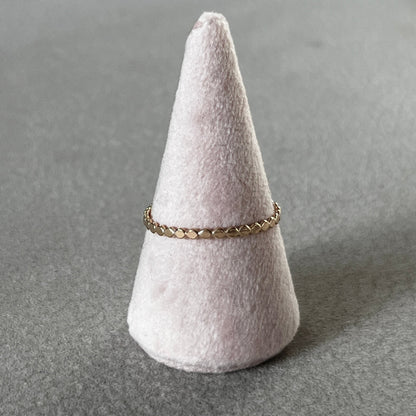 Gold ring on a gray cone-shaped jewelry stand against a gray background