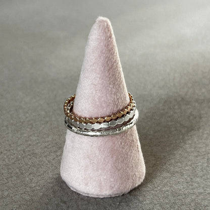 Three rings stacked on a gray felt ring holder against a gray background