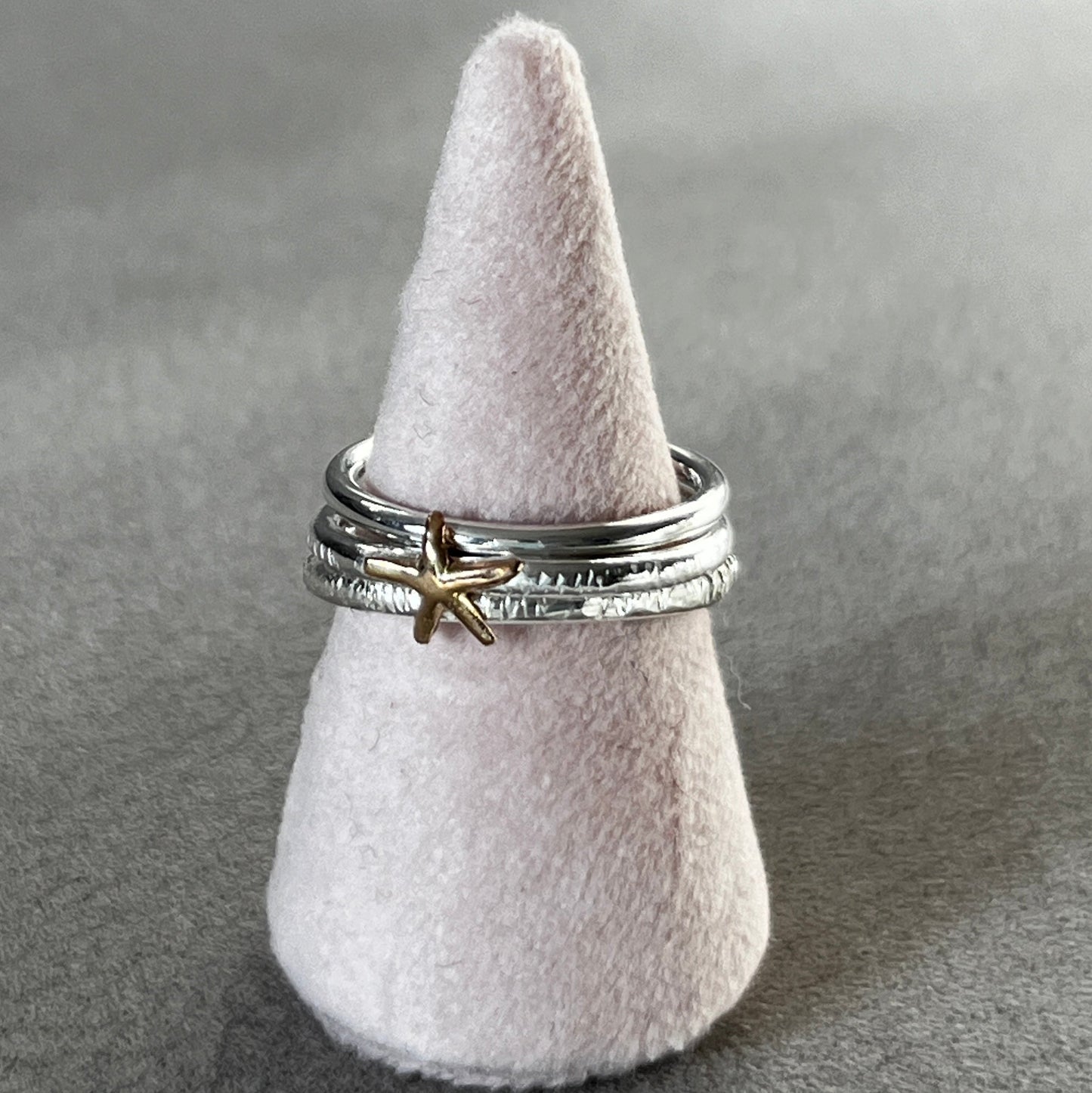 Silver ring with a starfish charm on a gray surface