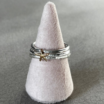 Silver ring with a starfish charm on a gray surface
