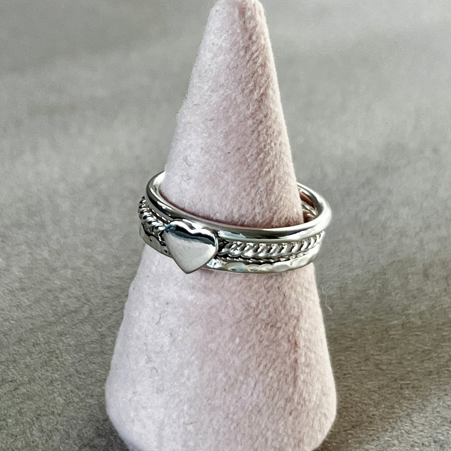 Silver ring with a heart design on a gray surface