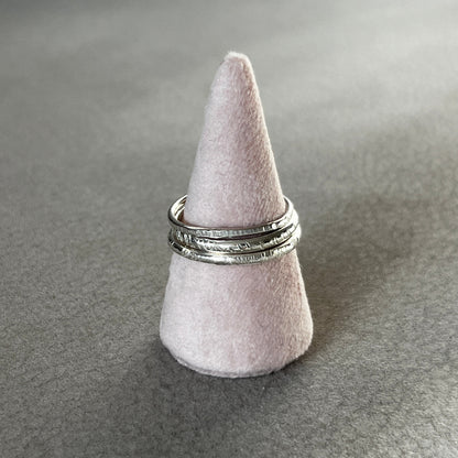 Silver ring on a gray felt cone stand against a gray background