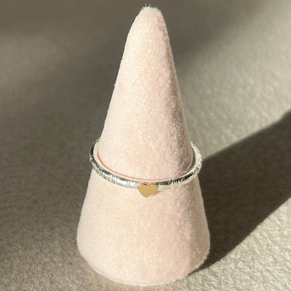 Ring on a pink cone-shaped stand with a heart detail on a beige background