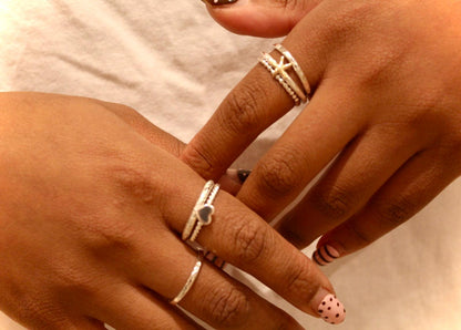 Close-up of hands with multiple silver rings on a neutral background