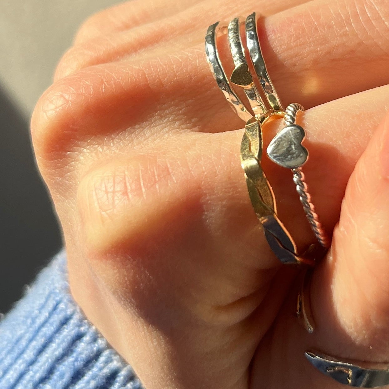 Hand wearing multiple silver rings with a blurred background