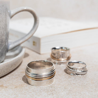 sterling silver spinner textured finished with downward bark like markings finished 3 gold filled outer rings shown here with a cup and a book