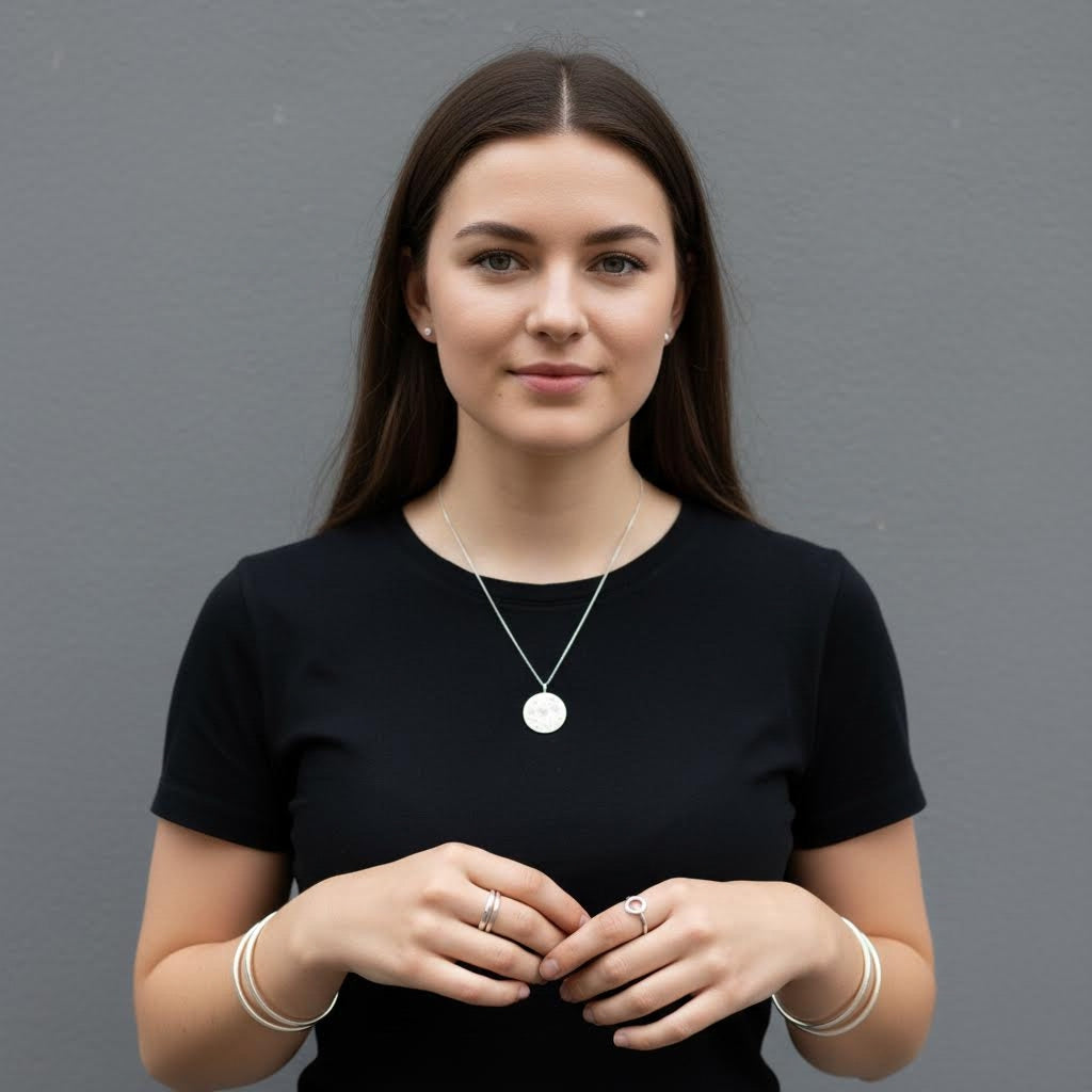 Woman wearing a black shirt with a necklace against a gray background