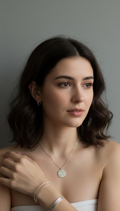 Woman wearing a necklace and bracelets against a neutral background