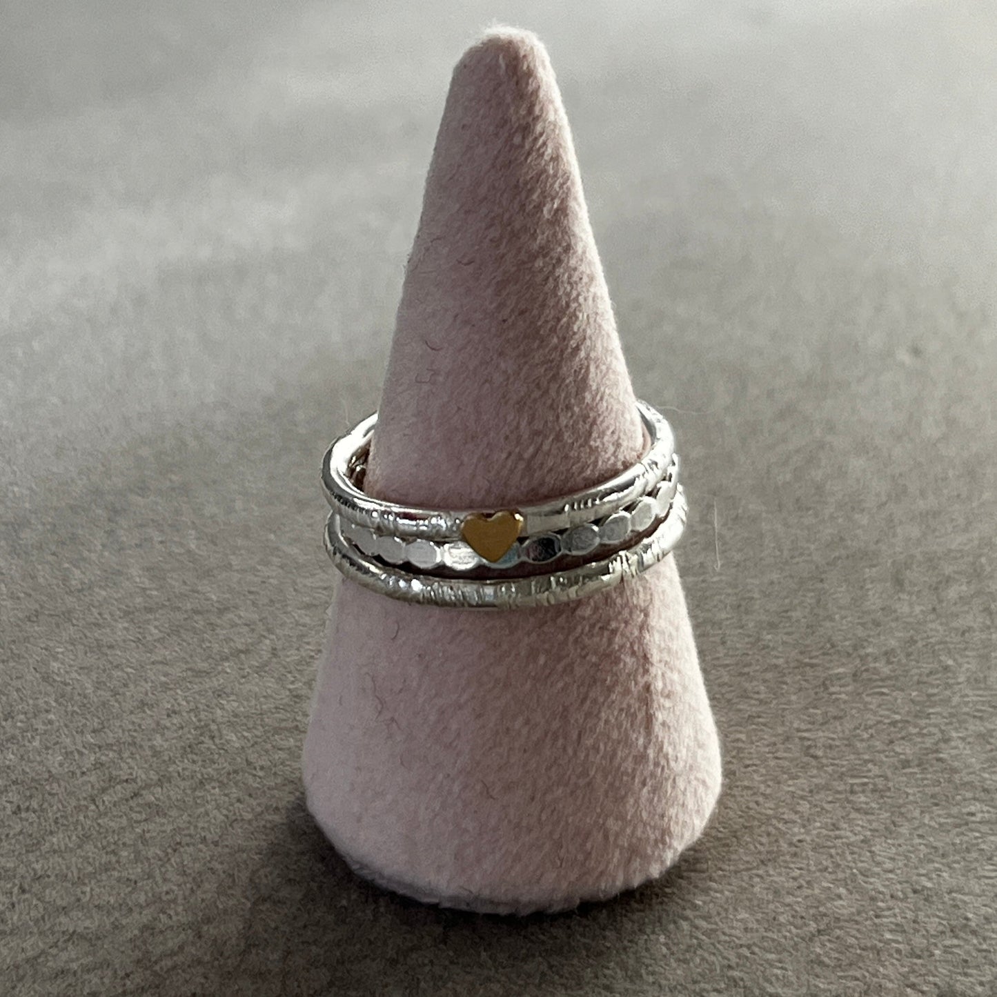 Two silver rings stacked on a cone-shaped gray stand against a gray background