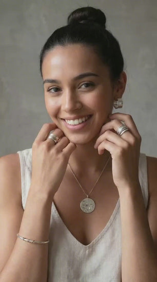 young woman showing silver earrings pendant and burrnen spinner ring