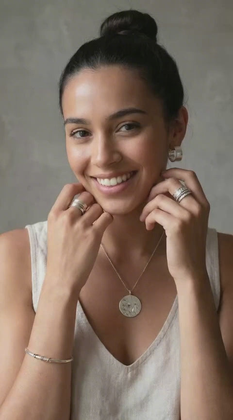 young woman showing silver earrings pendant and burrnen spinner ring