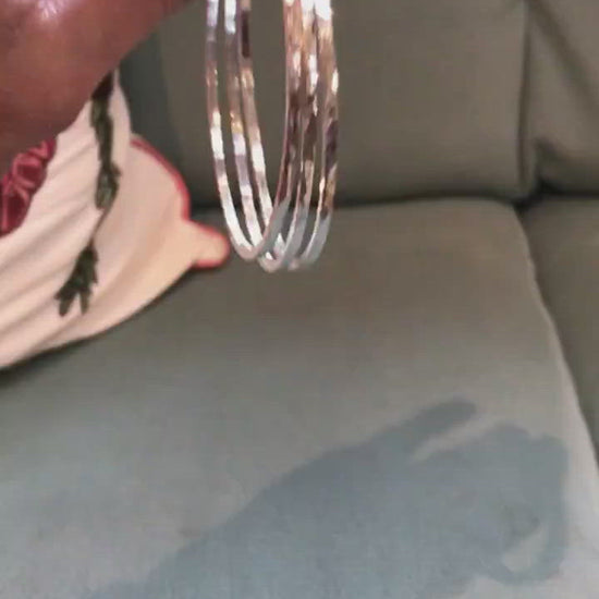 sterling silver handmade bangle, 2mm square wire hammered and polished to a high shine - made in Dublin Ireland boomerang video shows three polly stacking bangles bouncing on a green chair