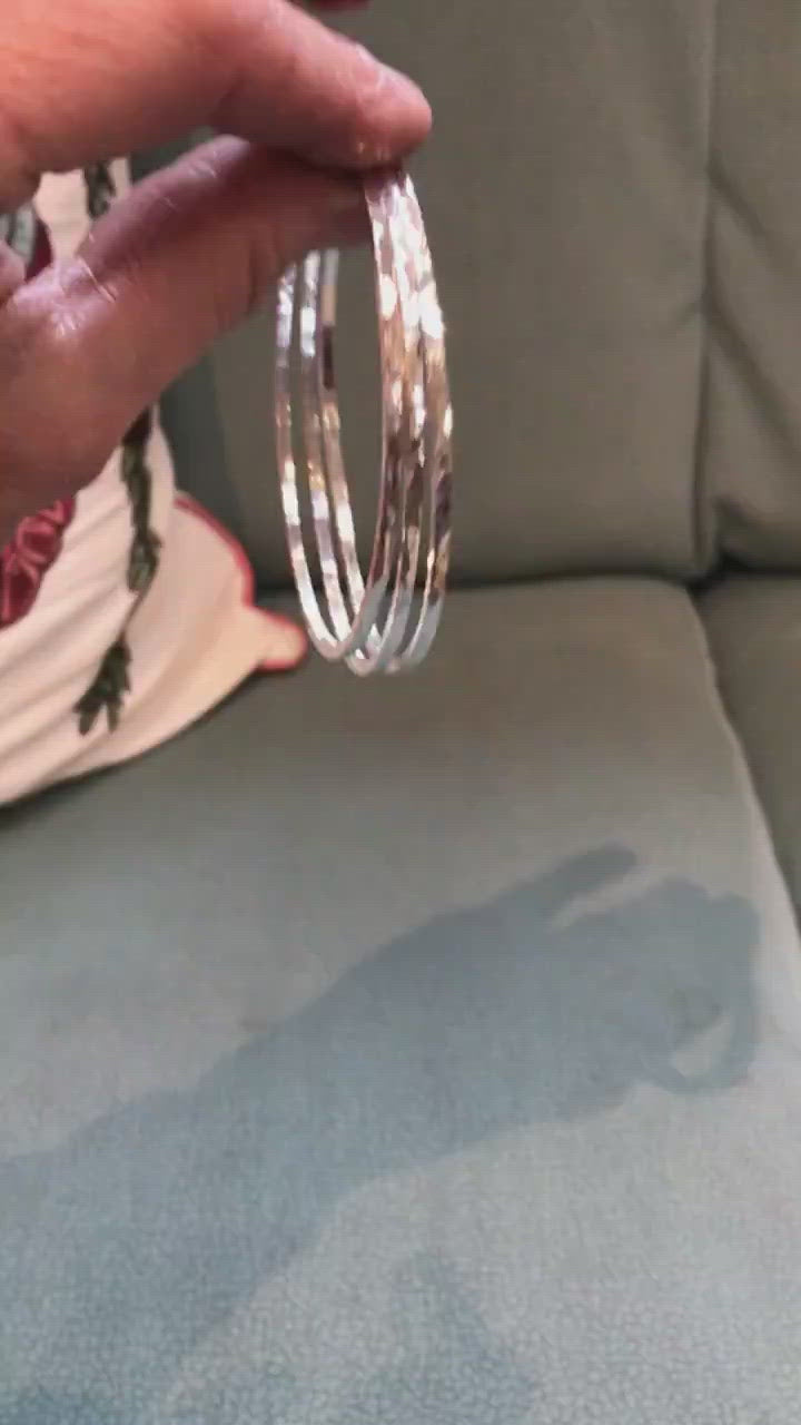 sterling silver handmade bangle, 2mm square wire hammered and polished to a high shine - made in Dublin Ireland boomerang video shows three polly stacking bangles bouncing on a green chair