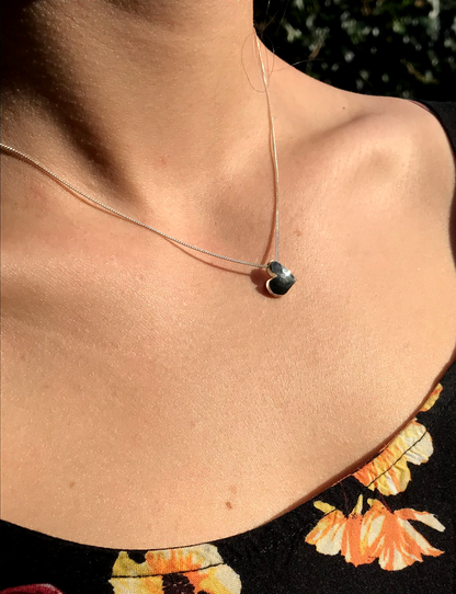 beautiful handmade in Dublin Sweetheart sterling silver necklace model is wearing a black top with orange and yellow flowers