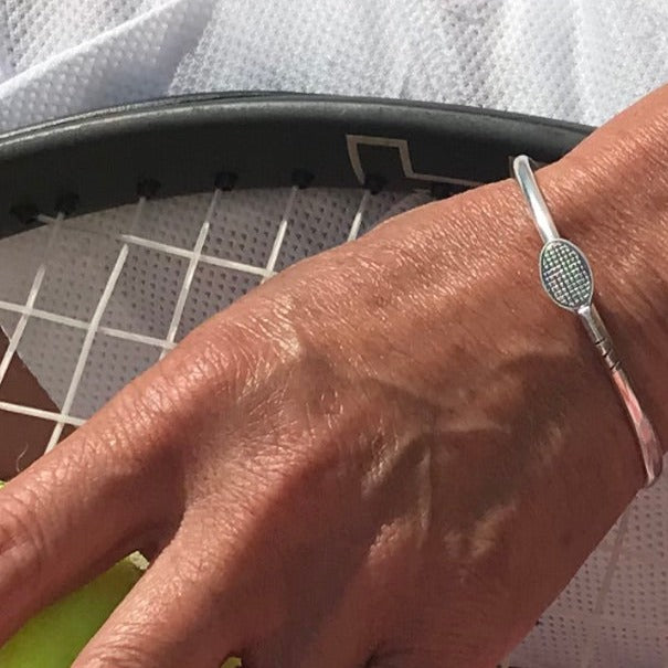Handmade sterling silver tennis bracelet bangle pictured on a tennis racket in Clontarf Tennis club