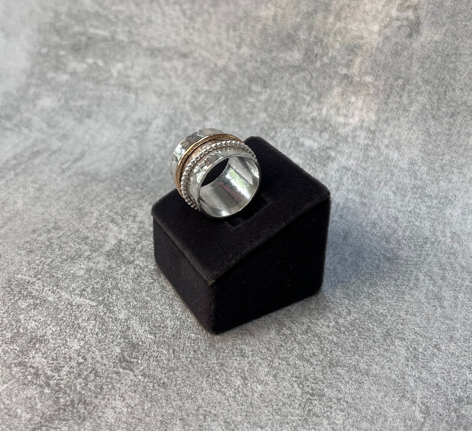 hammer finished spinner ring with a gold spinner and a silver spinner on a black velvet box