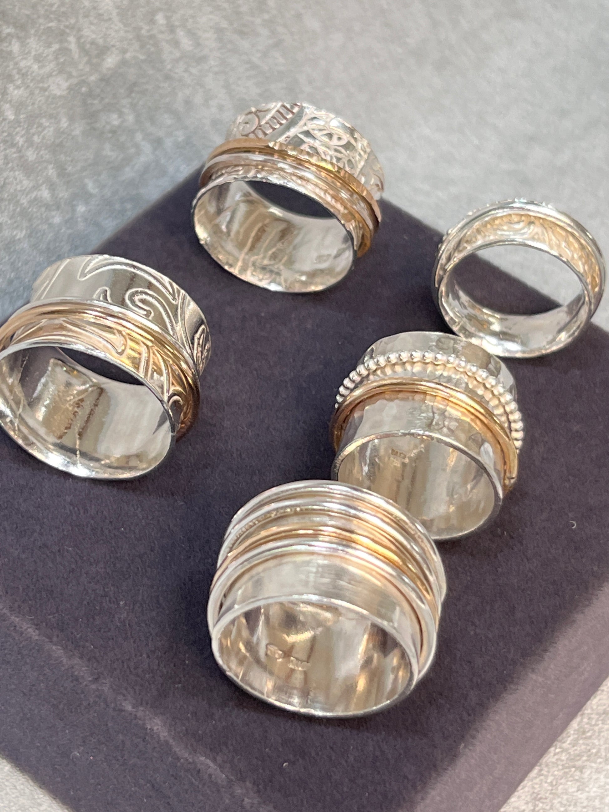 A collection of sterling silver spinner rings on a grey velvet base