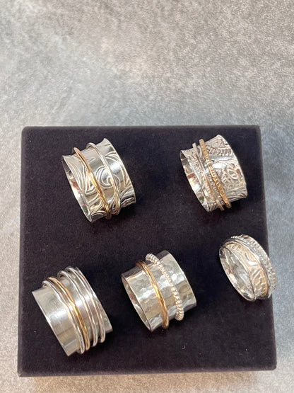 five spinner rings on display on a black velvet backround 