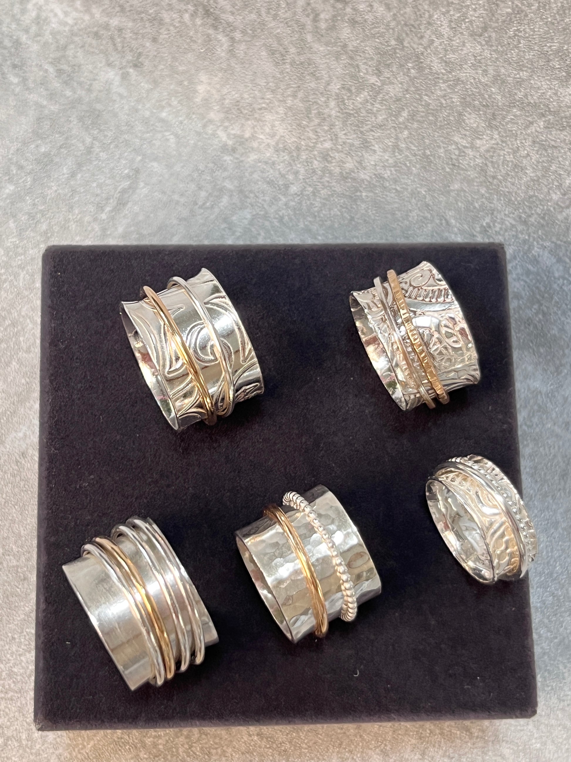 a collection of the various spinner rings available five in the picture on a black velvet stand