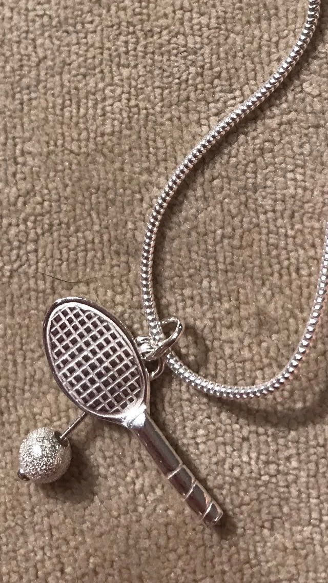 close up shot sterling silver handmade tennis racket racquet on sterling silver snake chain  cream velvet background