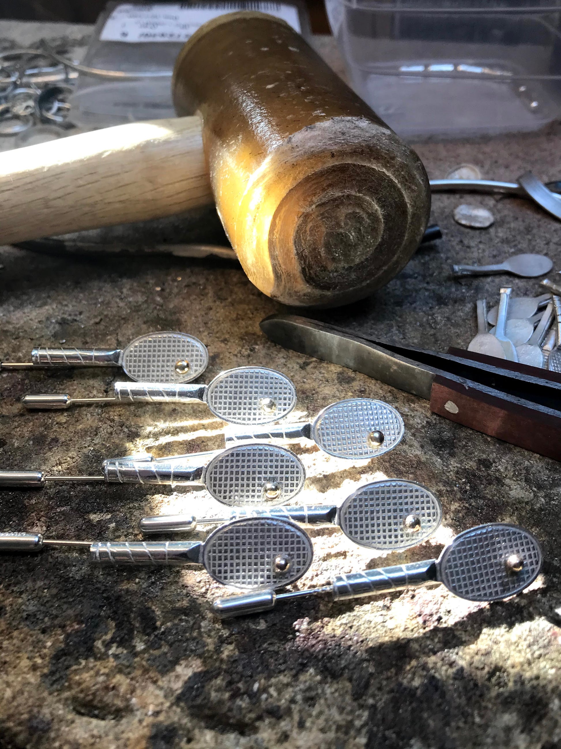 seven sterling silver tennis racket shaped broach/stick pins handmade with 9ct gold ball. Pictured with traditional rawhide mallet