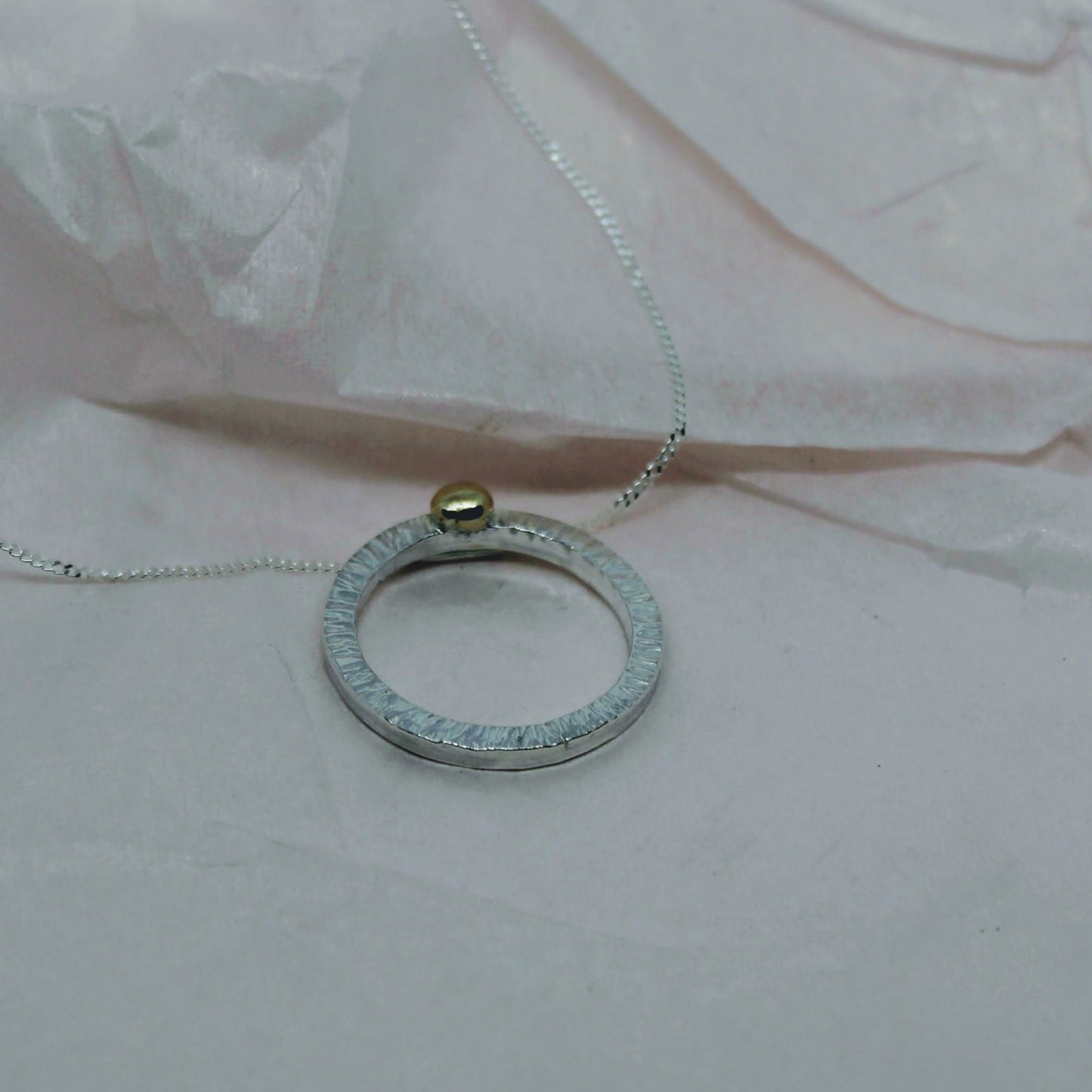 beautiful bright cut circle of silver with9ct gold ball pendant necklace pink background