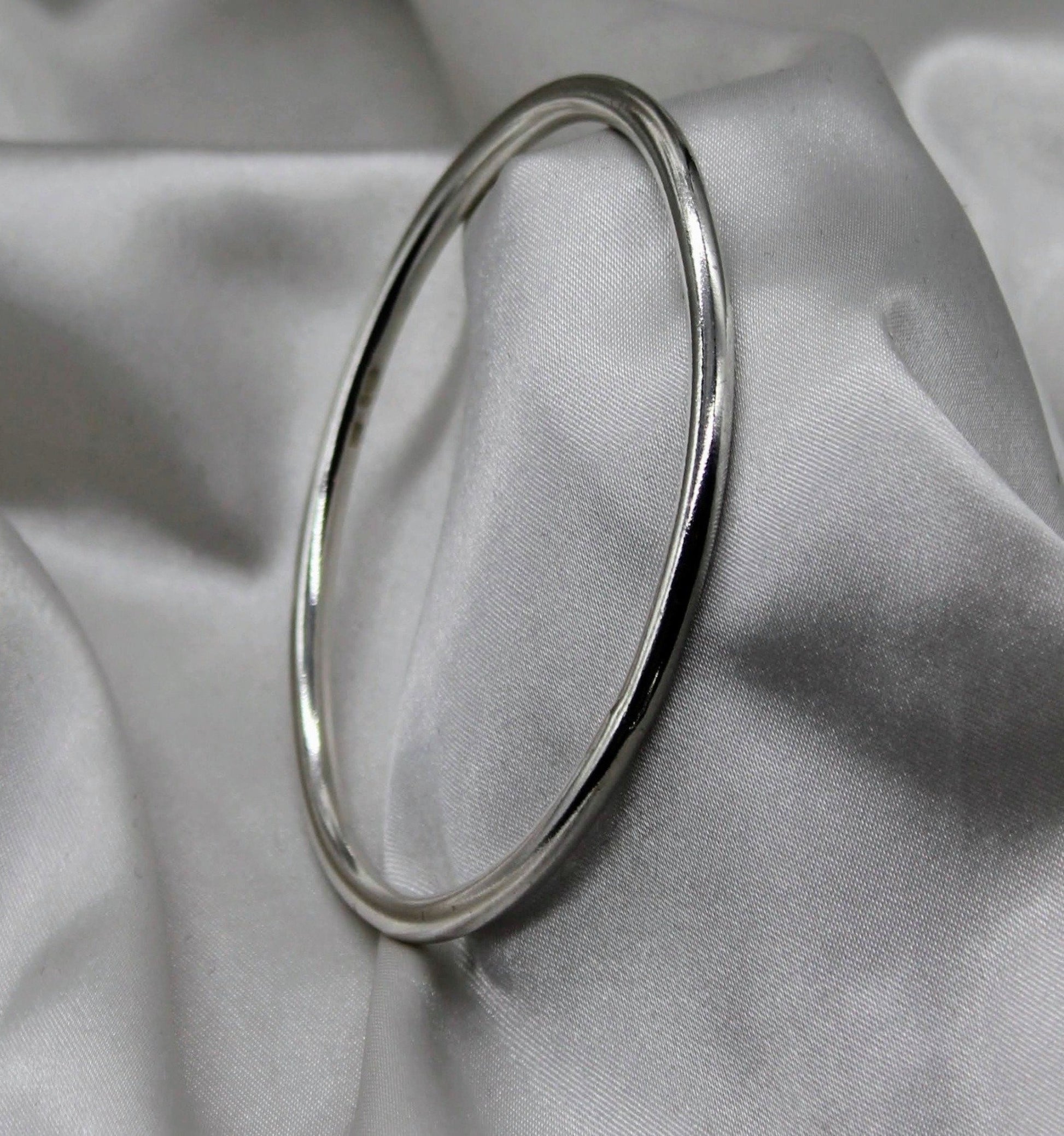 solid sterling silver bangle on a grey silk background